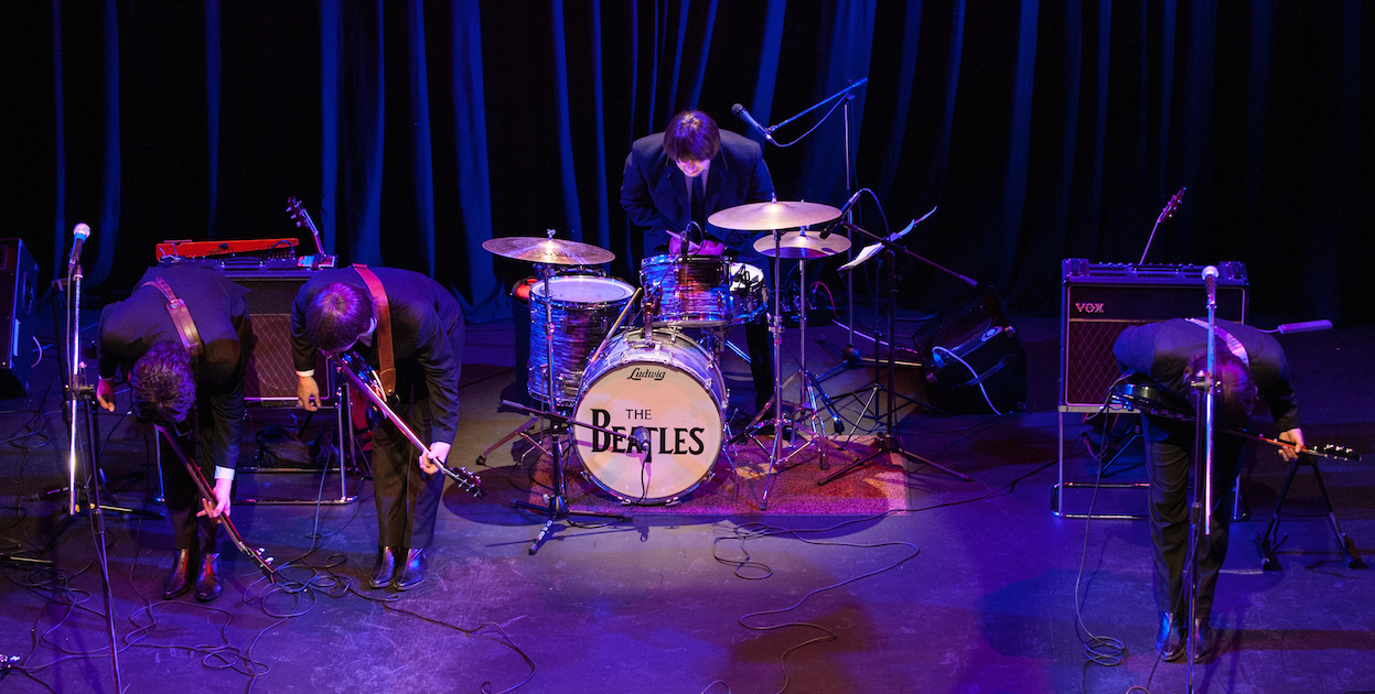 Ultimate Beatles Tribute Band bowing on stage